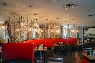 Cora's Restaurant at The White House Hotel with red booths, branch lights, and tables set for fine dining