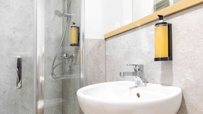 Modern bathroom with a white sink and shower at The Originals City Hotel du Parc Gravelines.