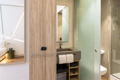 Bathroom interior with vanity, mirror, storage, and a frosted glass door in Standard Queen Room at Hotel Nodo