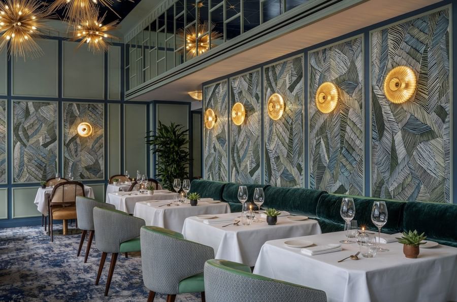 Dining area with tables, velvet bench under wall lights at The Capital Hotel, Apartments and Townhouse