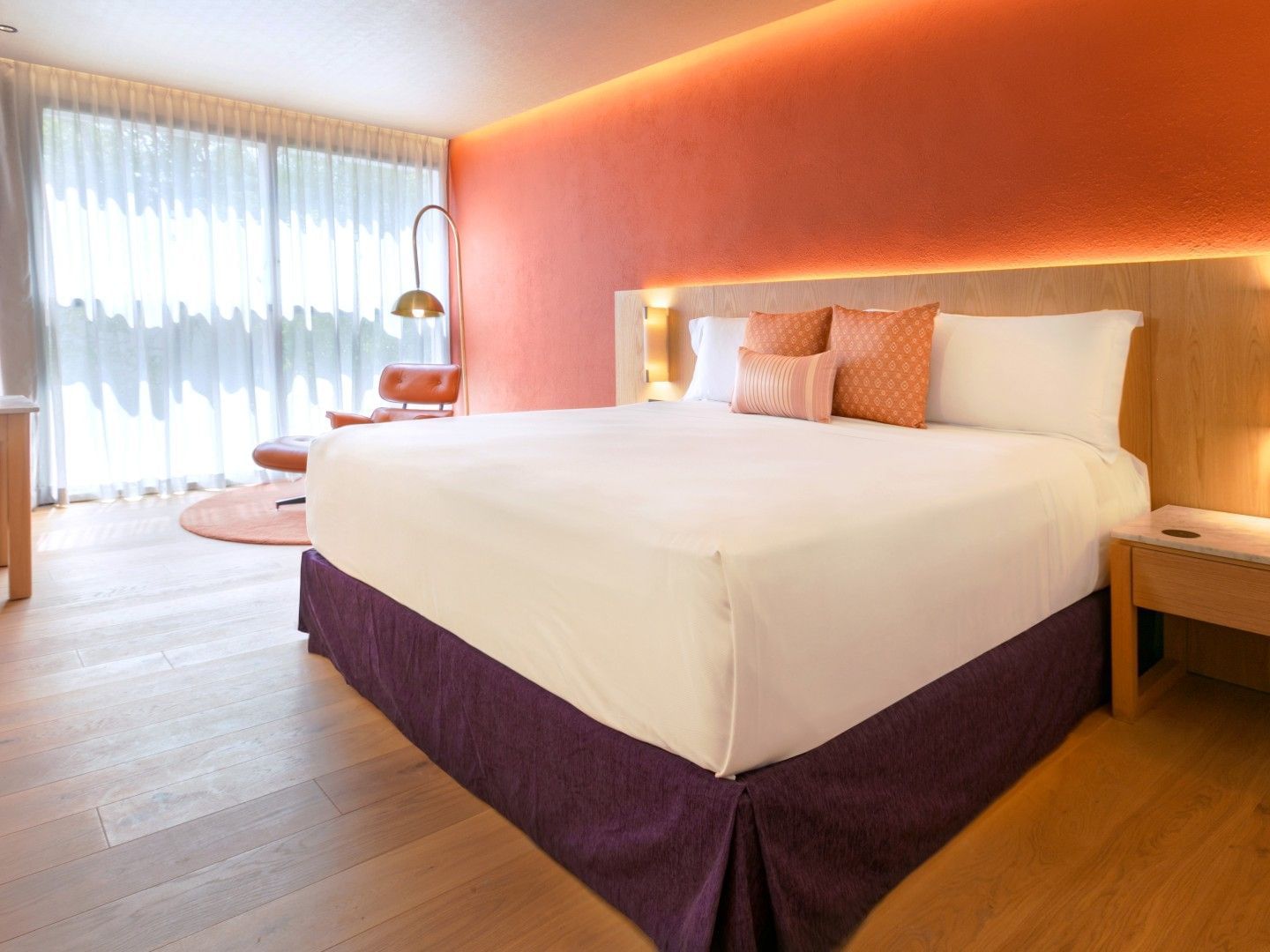 King Deluxe Plus room with an orange accent wall, wood floors, and a purple bed base at Camino Real Polanco Mexico