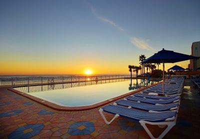 outdoor pool with lounge chairs and umbrellas