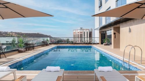 Sun loungers and dining tables set by the rooftop pool and city view at Warwick Al Taif Hotel