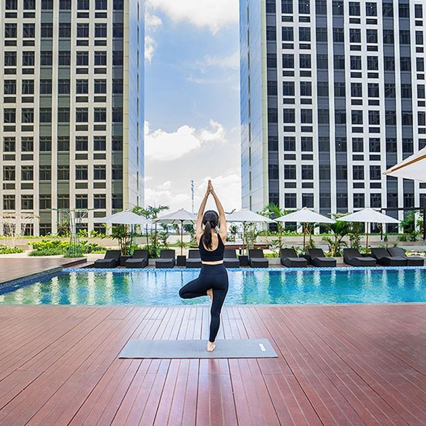Wanita melakukan yoga di dek tepi kolam renang di LK Cikarang Hotel & Residences