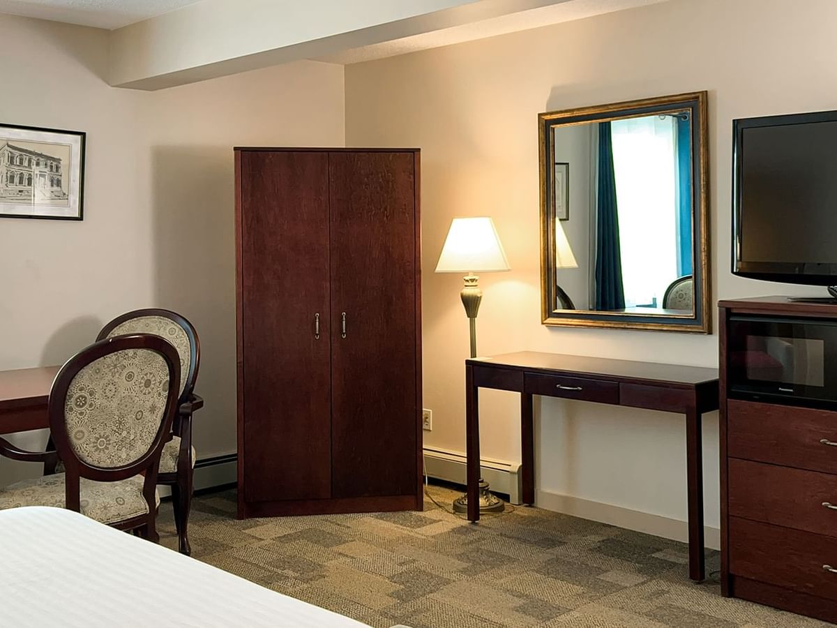 Bedroom suite with bed, mirror, window, chair, tv, and table