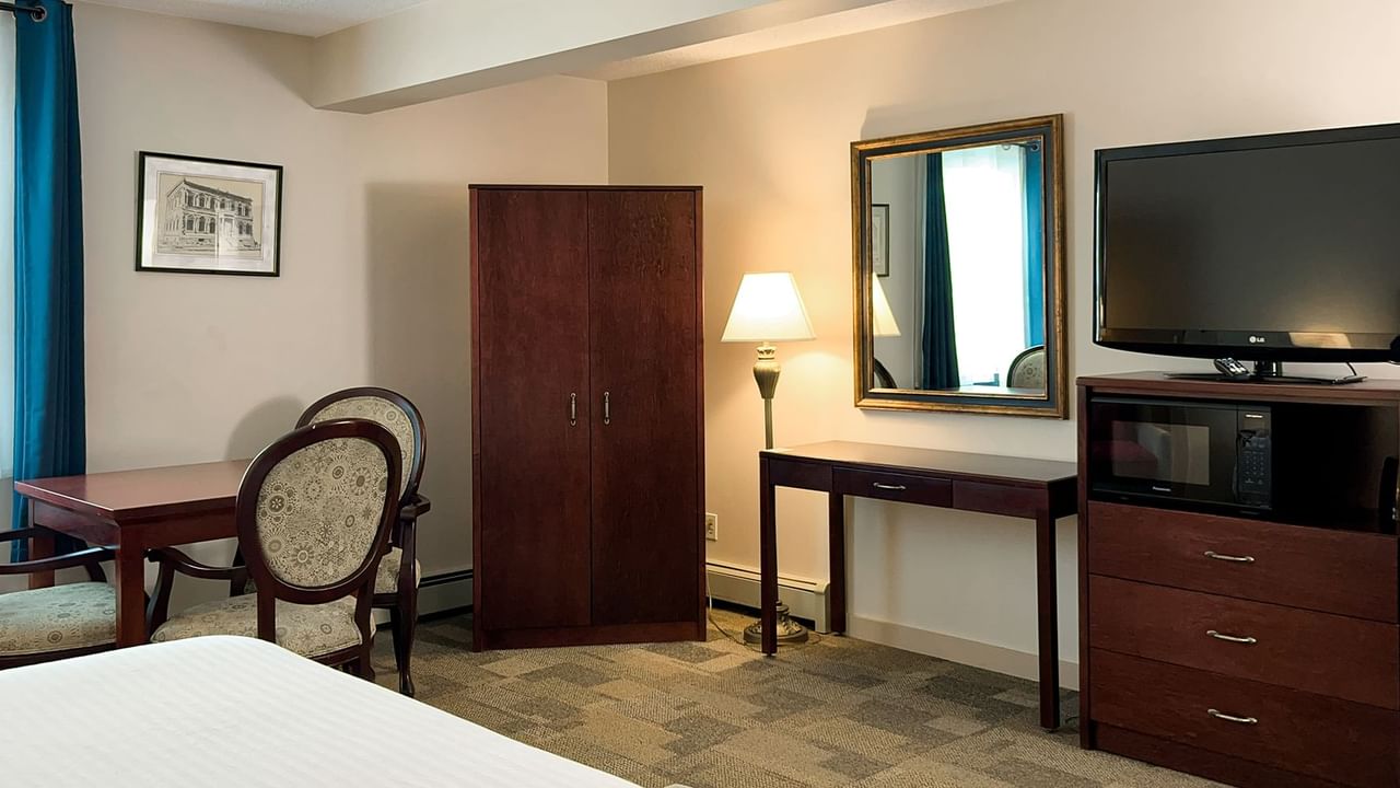 Bedroom suite with bed, mirror, window, chair, tv, and table