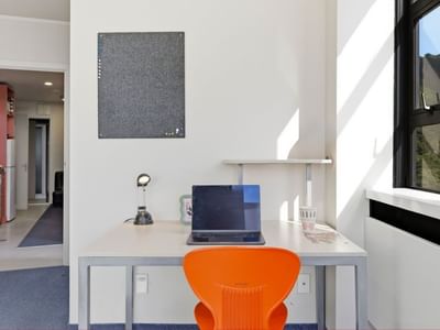 Modern room with desk, laptop, and orange chair at UniLodge Stafford House.