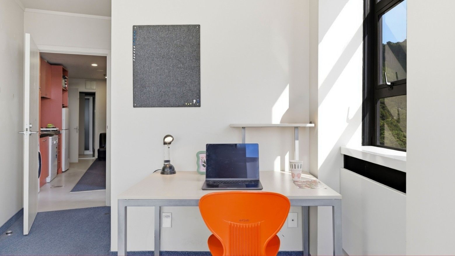 White room with desk, laptop, and orange chair at UniLodge Stafford House.