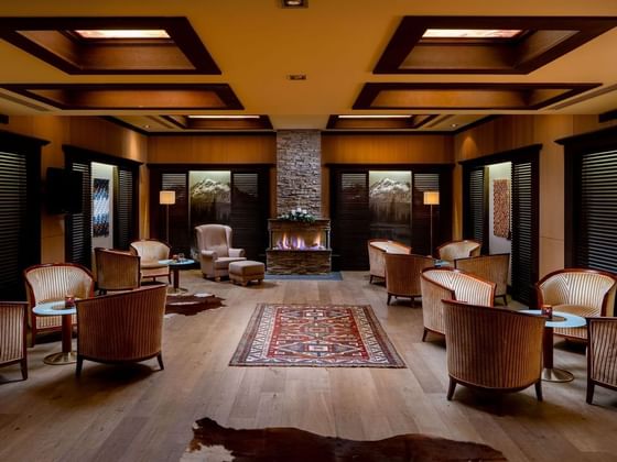 Lobby Bar with patterned chairs, fireplace and warm lighting at Ana Hotels Sport Poiana Brașov