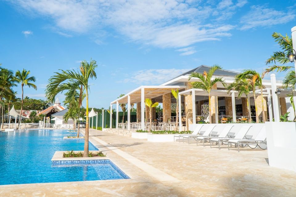 Outdoor pool with sun loungers & palm trees at Club Hemingway