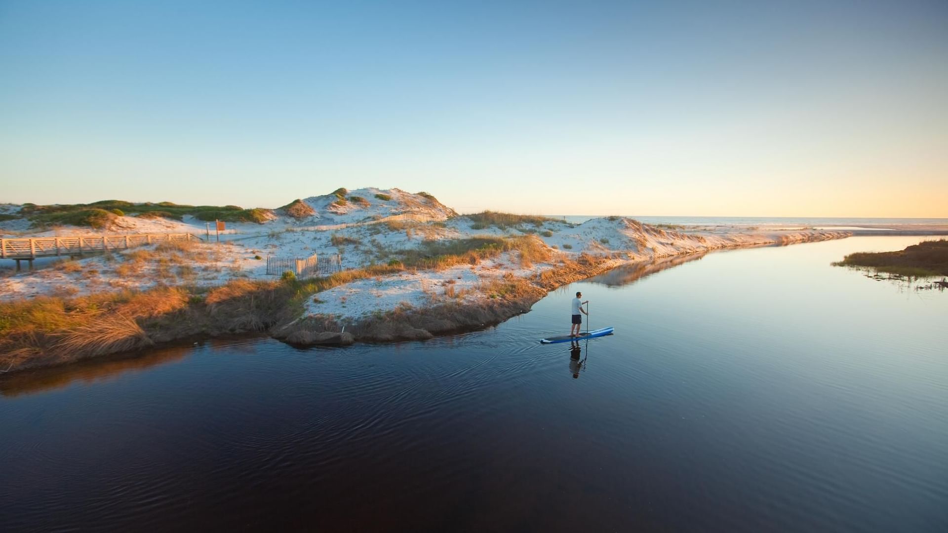 Sky view of a man on a paddleboard in the sea near Watersound Inn