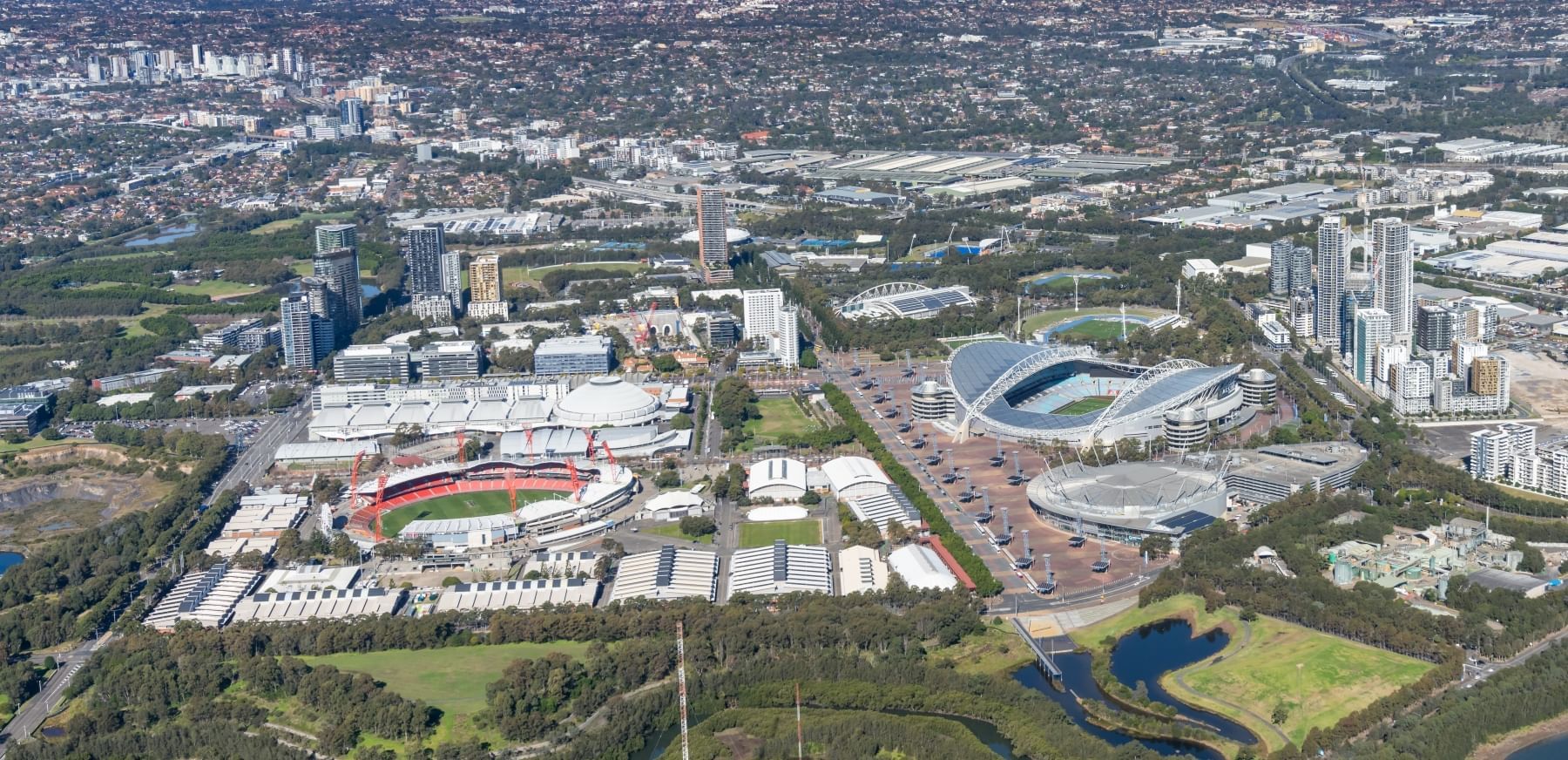 Impressive aerial view of Sydney's sporting precinct, featuring stadiums, Novotel Sydney Olympic Park & the city skyline
