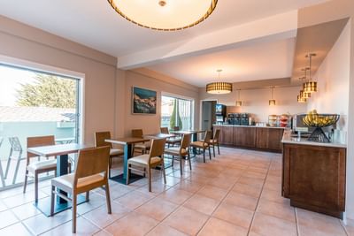 The sunny and inviting breakfast area with seating and a food bar featuring a large window at Carmel Bay View Inn