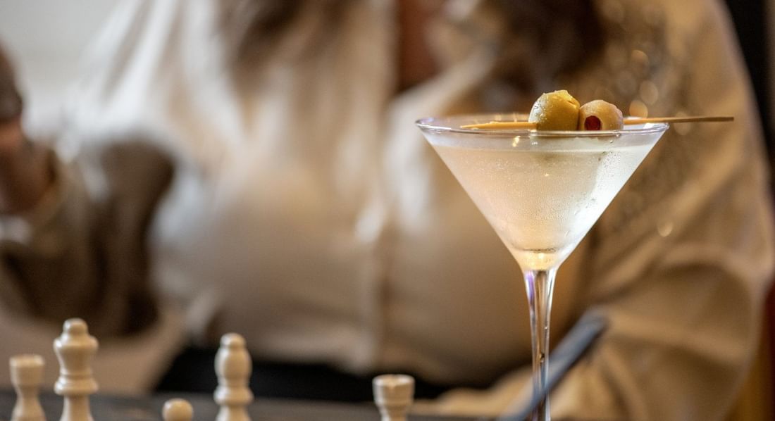 Chilled martini glass with olives served by a guest in Allerton Hotel Lobby Lounge at Warwick Allerton Chicago