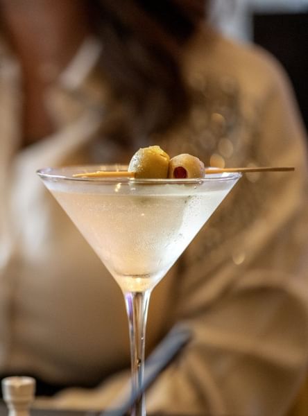 Chilled martini glass with olives served by a guest in Allerton Hotel Lobby Lounge at Warwick Allerton Chicago