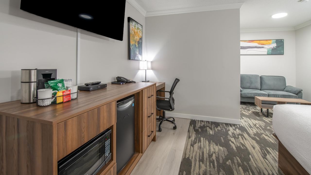 Hotel room with a desk, chair, couch, and microwave.