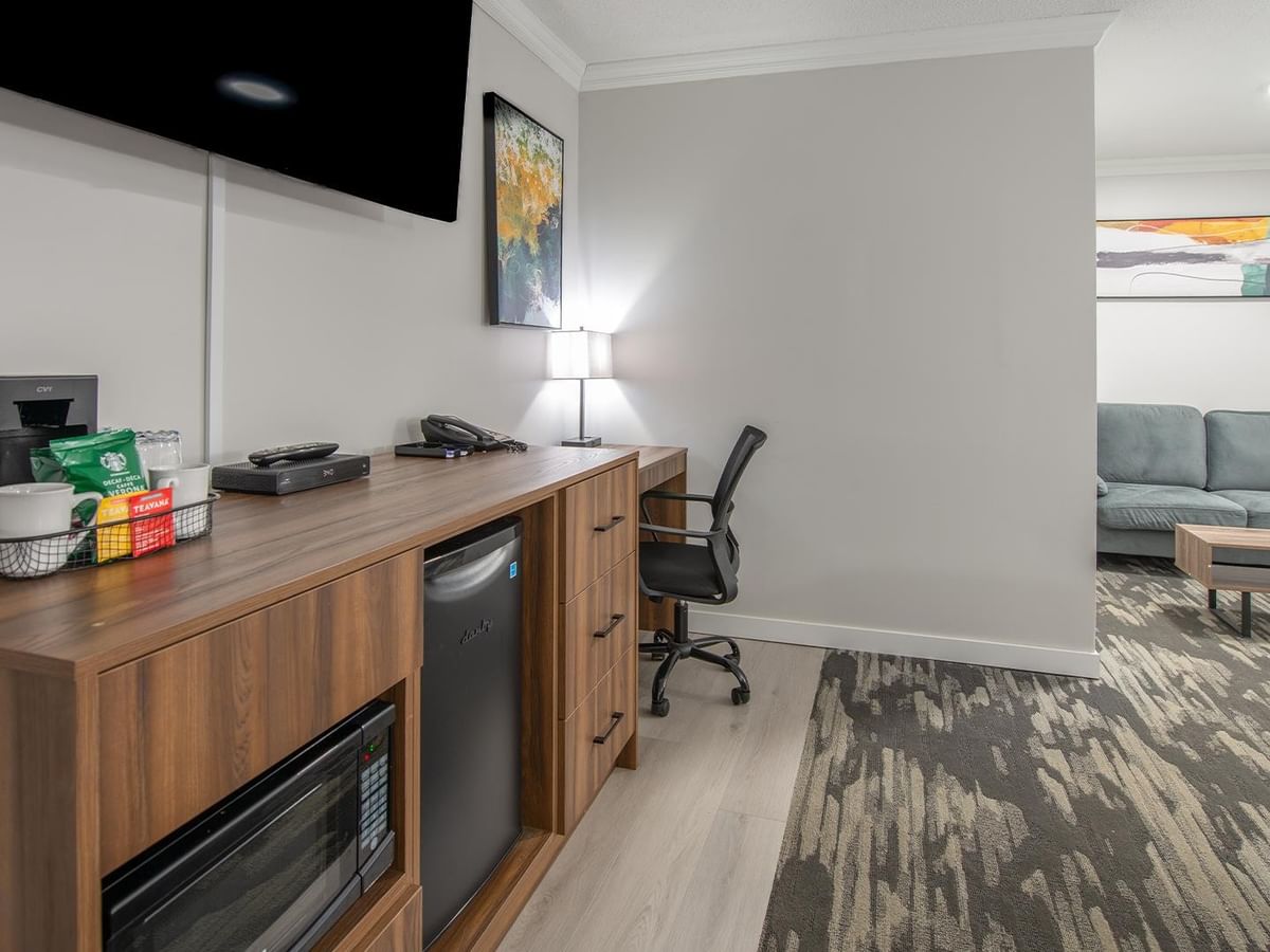 Hotel room with work desk, mini-fridge, TV, microwave, and couch.