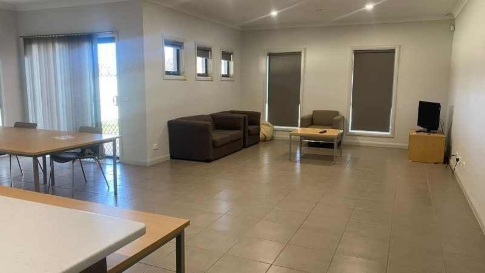 Spacious living room with couches, dining table, and TV at La Trobe University Regional Housing – Mildura.