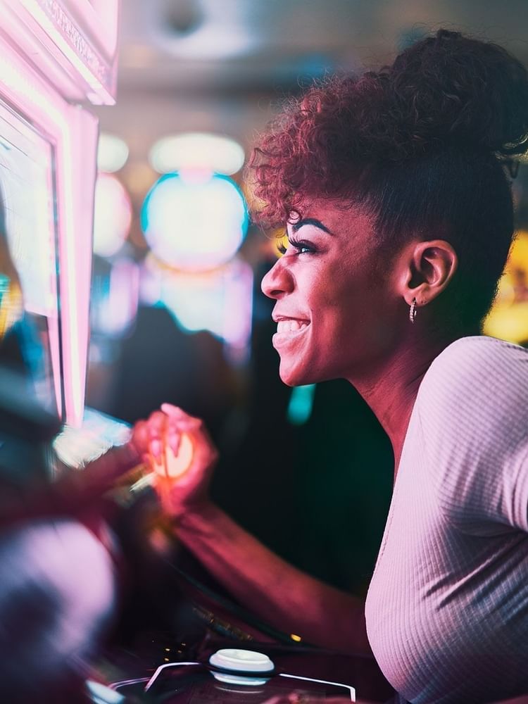 Smiling woman playing on a glowing slot machine in Casino Barrière Le Ruhl Nice near Splendid Hotel & Spa Nice