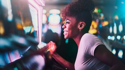 Smiling woman playing on a glowing slot machine in Casino Barrière Le Ruhl Nice near Splendid Hotel & Spa Nice
