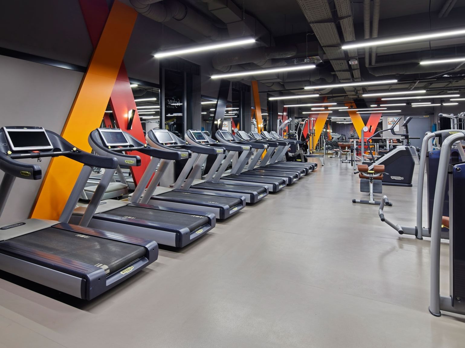 Modernes Fitnessstudio mit Laufbändern, Kraftgeräten und heller Beleuchtung – Titanic Chaussee Berlin.