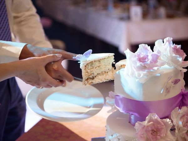 Closeup of a wedded couple slicing the cake at Warwick Melrose