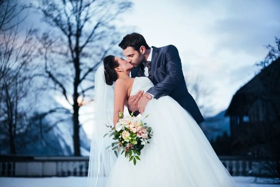 Groom kissing his bride outside at Schloss Hotel Pichlarn