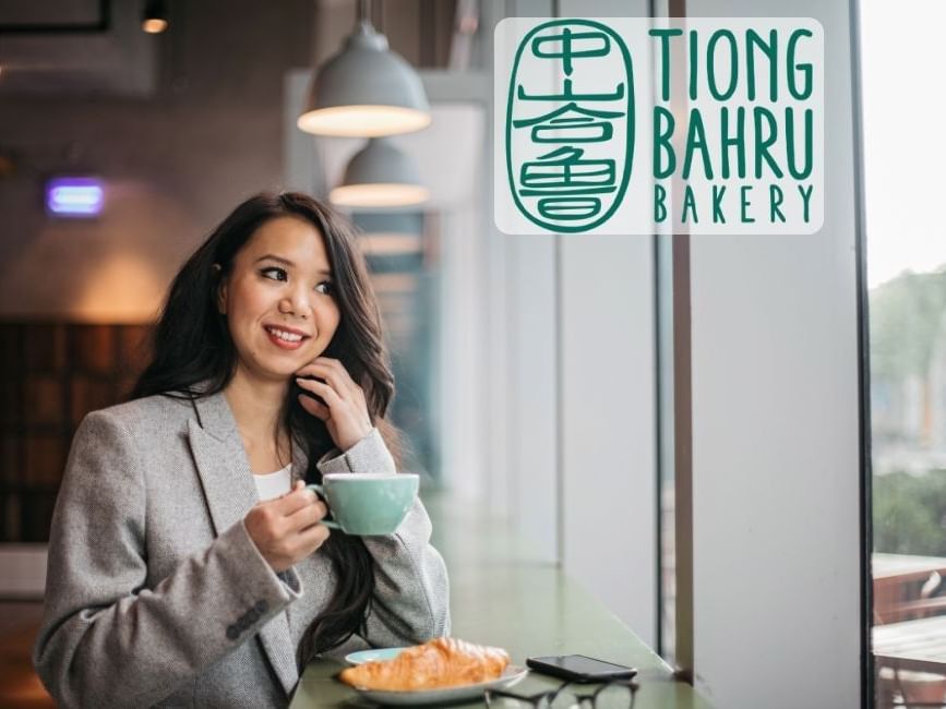 Woman smiling with coffee at Tionh Bahru Bakery.
