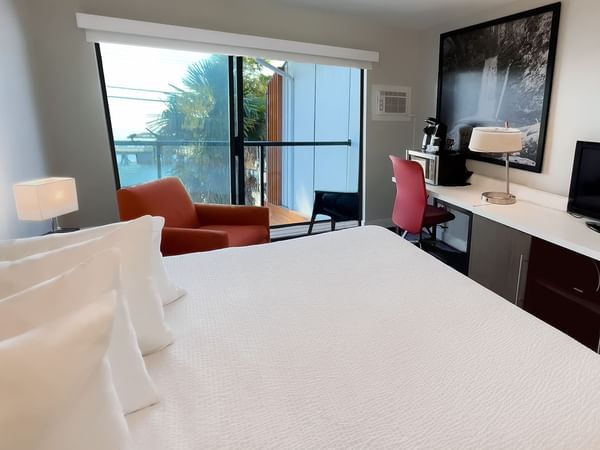 Guest room with king bed, tv, desk, chairs, balcony, ocean view