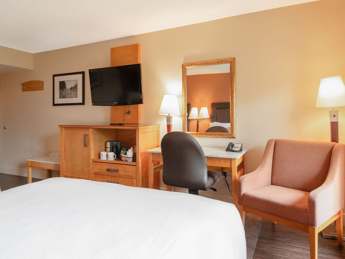 Hotel guest room with two queen beds, a work desk, TV, and arm chair