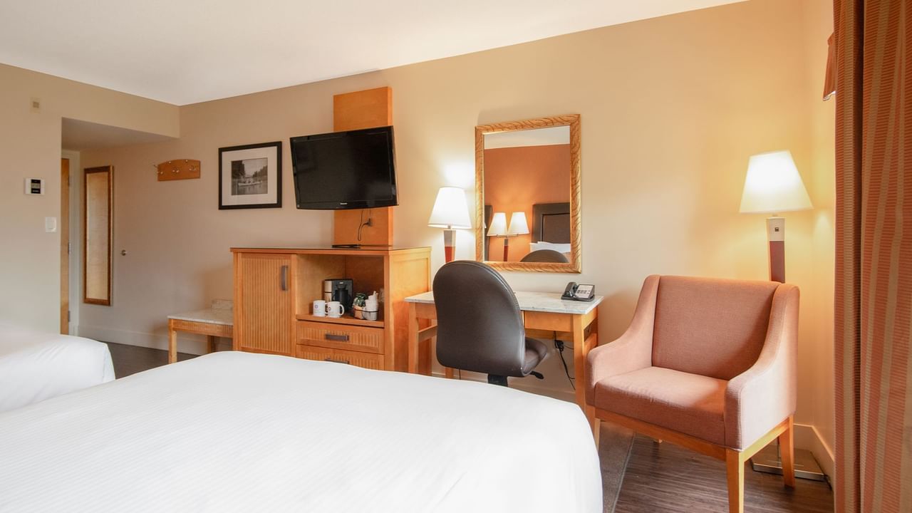 Hotel guest room with two queen beds, a work desk, TV, and arm chair
