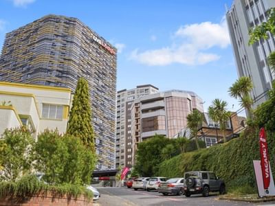 UniLodge Auckland City building with cars parked outside on a sunny day.