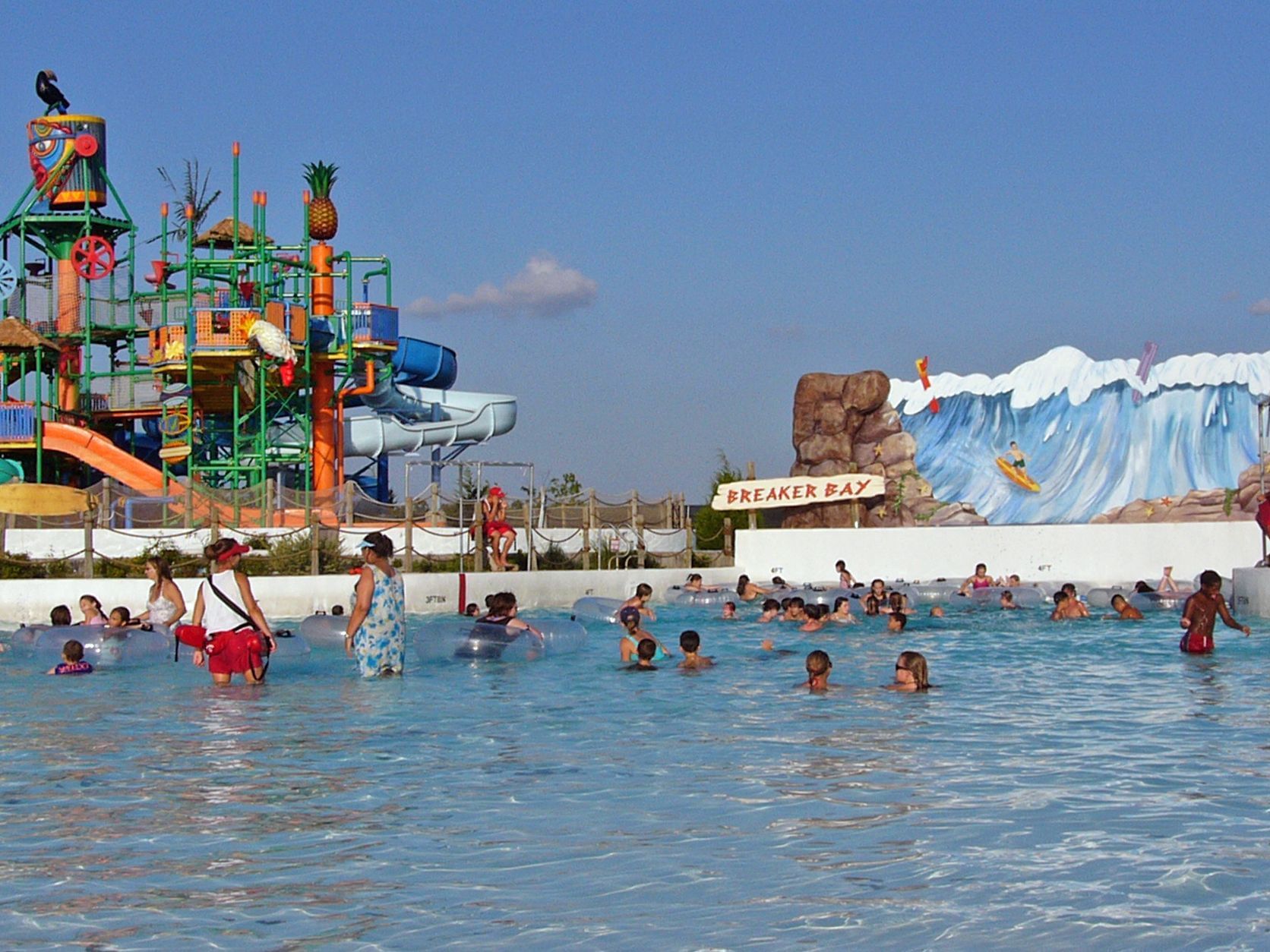 people swimming in large pool with water slide in background