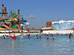 people swimming in large pool with water slide in background