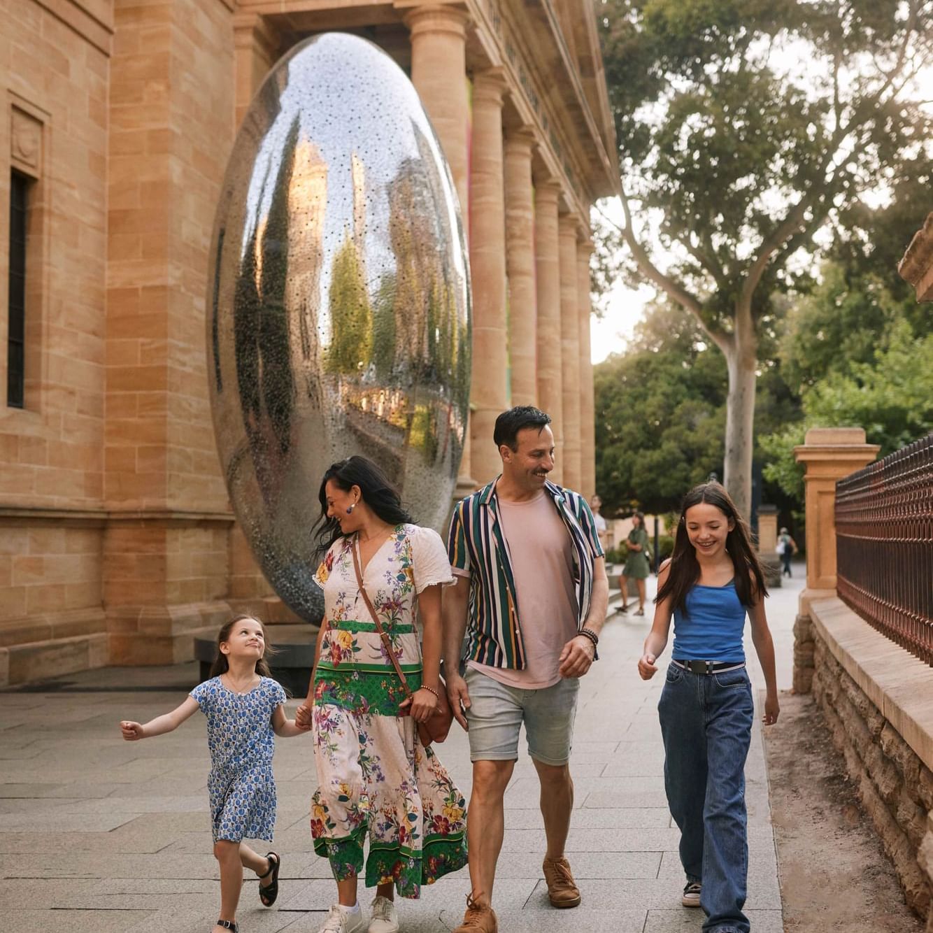 Family strolls past a reflective art installation on a sunny day during Adelaide School Holidays.