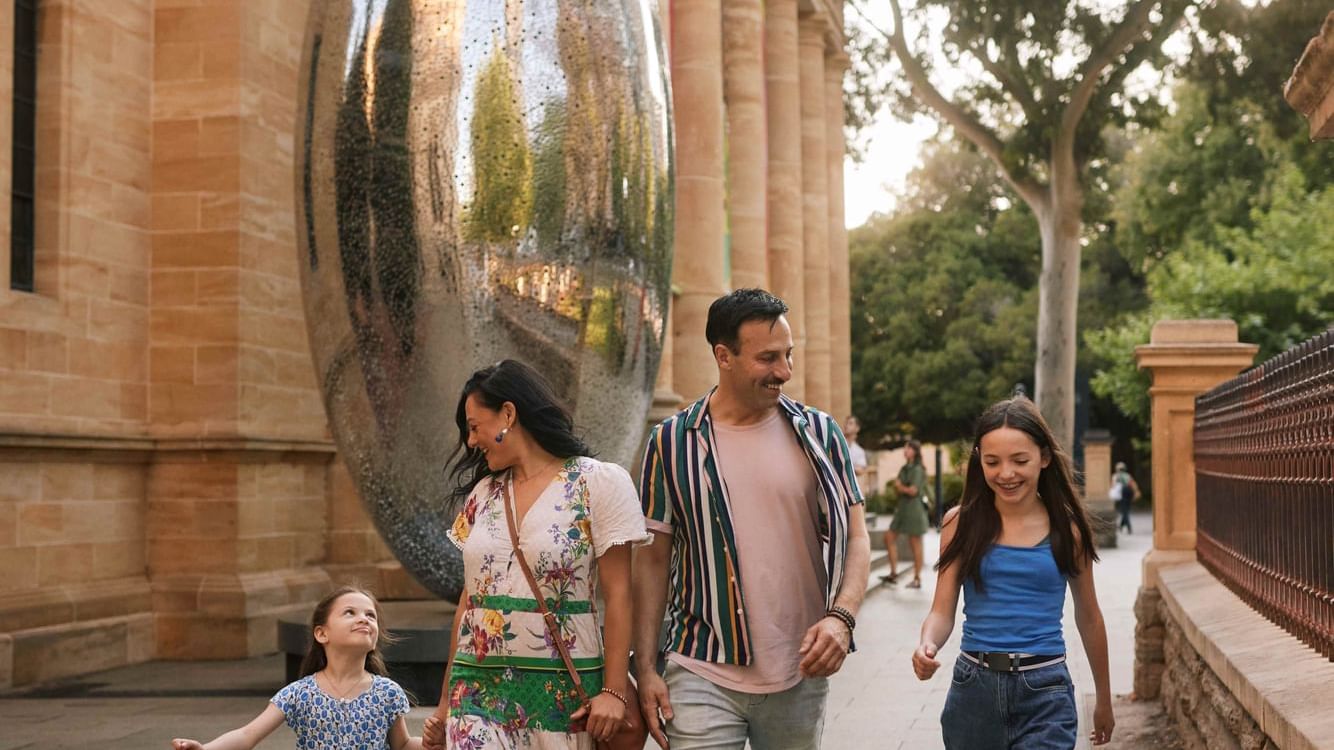 Family strolls past a reflective art installation on a sunny day during Adelaide School Holidays.