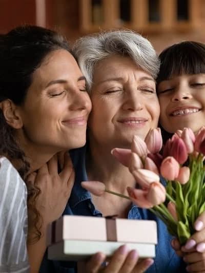 Girl and woman hugging an elderly lady by a pink gift box near tulips at Warwick Paris Champs Elysées
