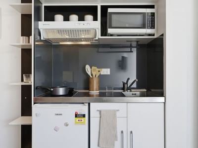 Compact kitchen with microwave, fridge, and cooking essentials at UniLodge Auckland City.