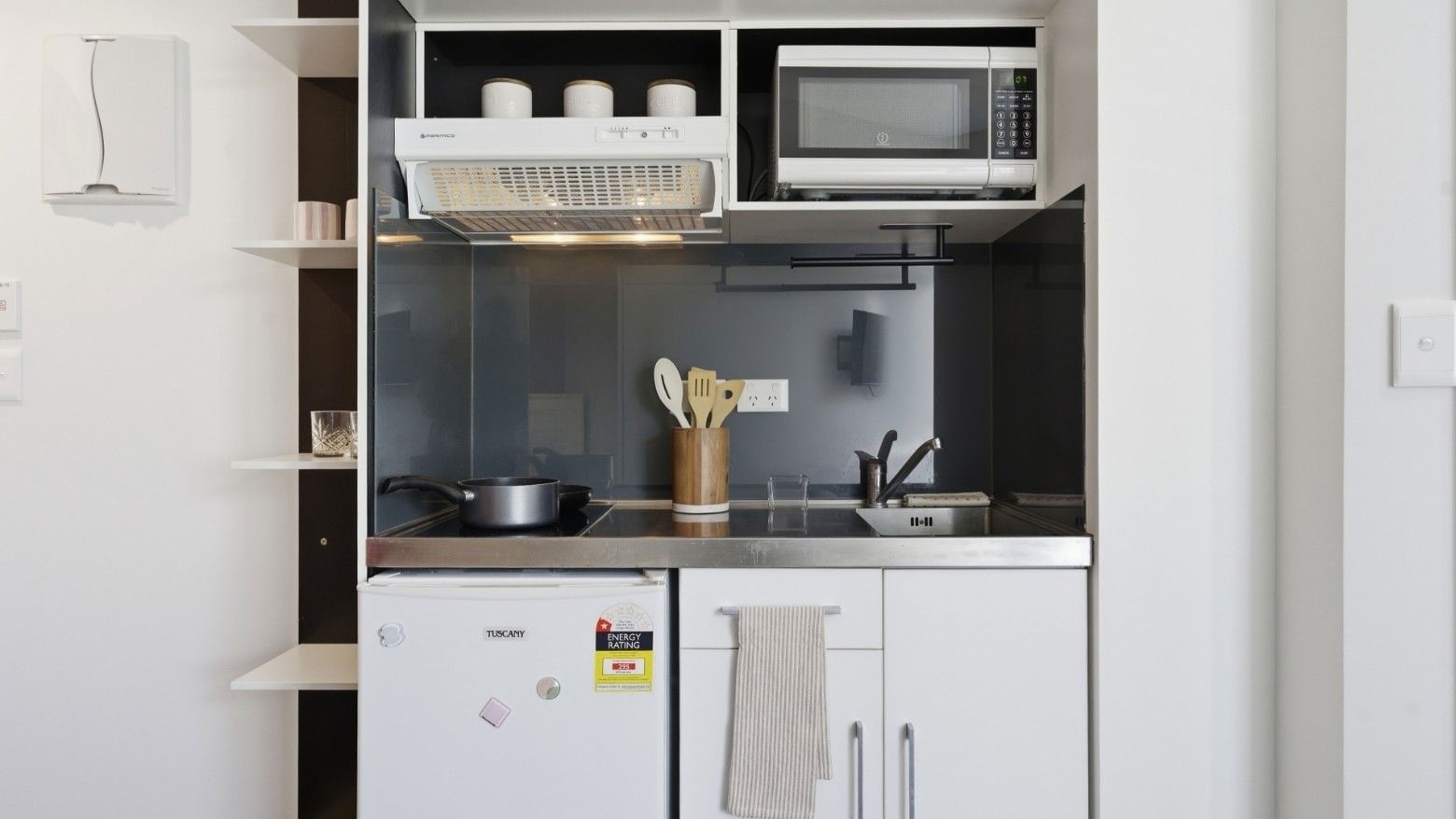 Compact kitchen with microwave, fridge, and cooking essentials at UniLodge Auckland City.