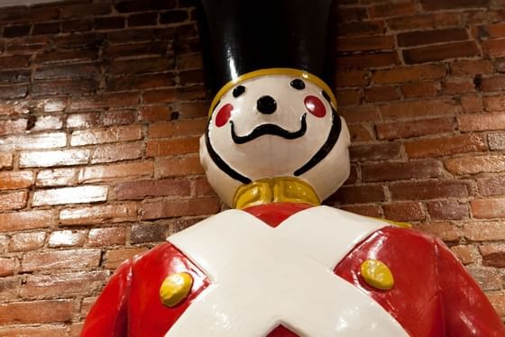 Low-angle shot of nutcracker statue in red and white by a brick wall at Retro Suites Hotel