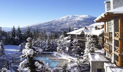 Snow-covered exterior view of Blackcomb Springs Suites with a mountain backdrop