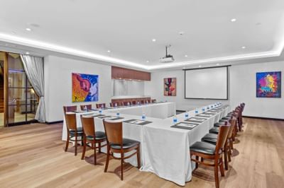 The J Gallery with a U-shaped table setup facing a projector screen at The J House Greenwich