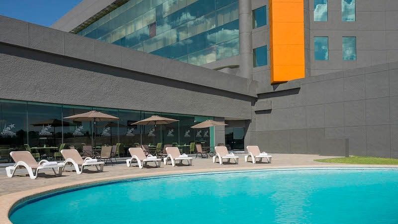 Outdoor swimming pool area at the Real Inn Nuevo Laredo hotel, featuring lounge chairs and umbrellas