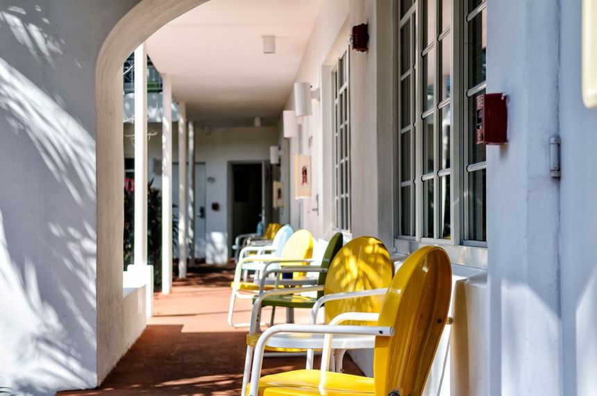 Outdoor walkway balcony with brightly colored yellow and green chairs offering a sunny spot at Tradewinds Apartment Hotel