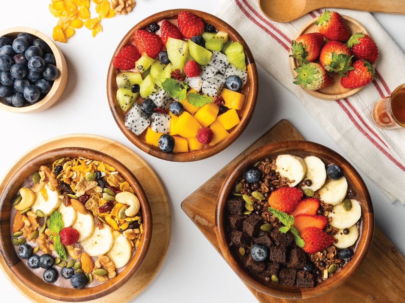  Assorted bowls of fruit, nuts, and cereal.
