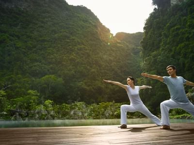 Couple doing yoga poses on the deck in Yoga class at The Banjaran Hotsprings Retreat