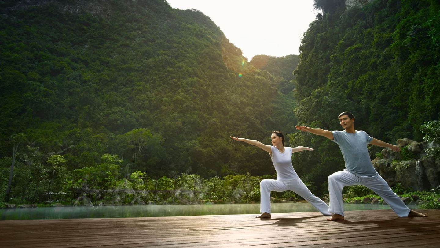Couple doing yoga poses on the deck in Yoga class at The Banjaran Hotsprings Retreat