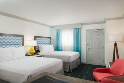 two beds and a chair in a hotel room