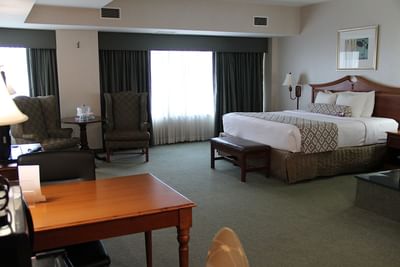 Executive Jacuzzi Suite with plush bed and wooden work desk beside comfortable armchair seating area at Clayton Plaza Hotel