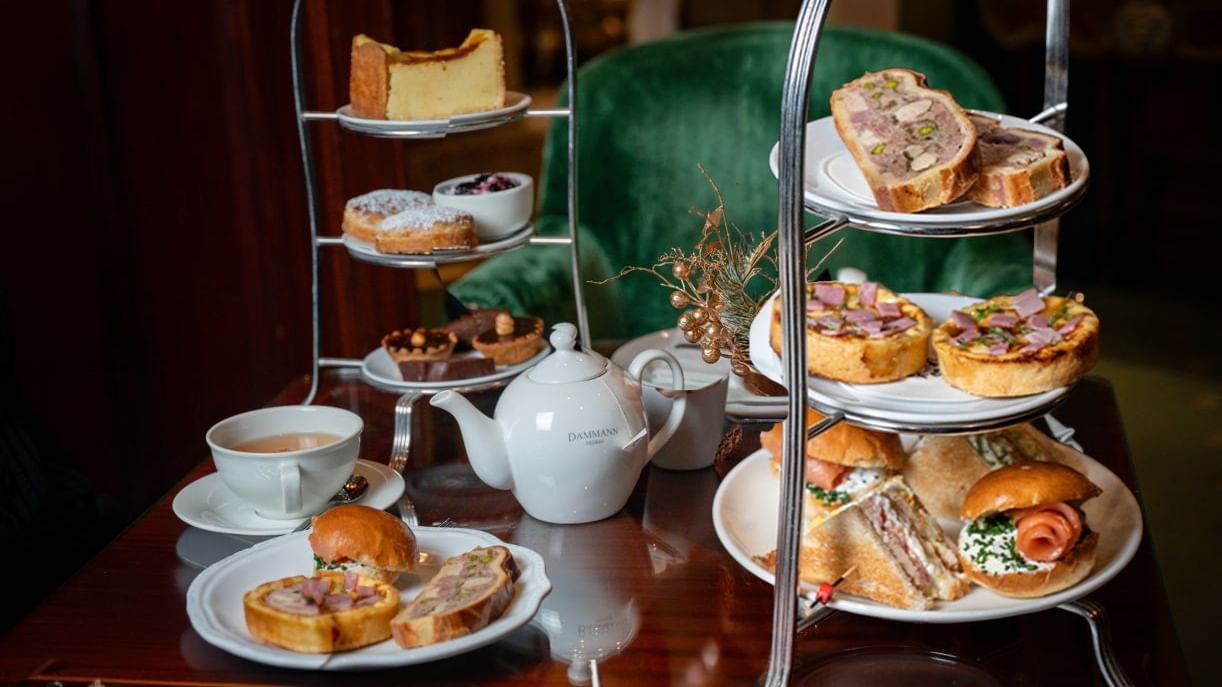 Afternoon tea spread with pastries and sandwiches served on the wooden table at Hotel Westminster Paris